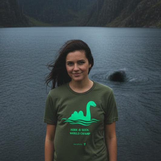 Nessie Hide and Seek World Champ cryptid graphic tee — green Loch Ness Monster silhouette on military green — Stitch and Sigil