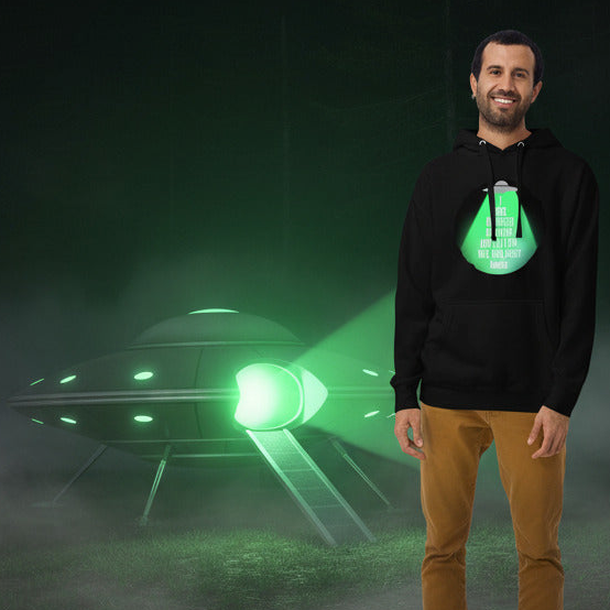 Person wearing a black hoodie with a green alien design in front of a UFO.