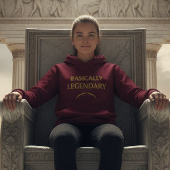 A woman sits on an ornate stone throne wearing a burgundy hoodie with gold text that reads 'BASICALLY LEGENDARY' and dark gray pants.