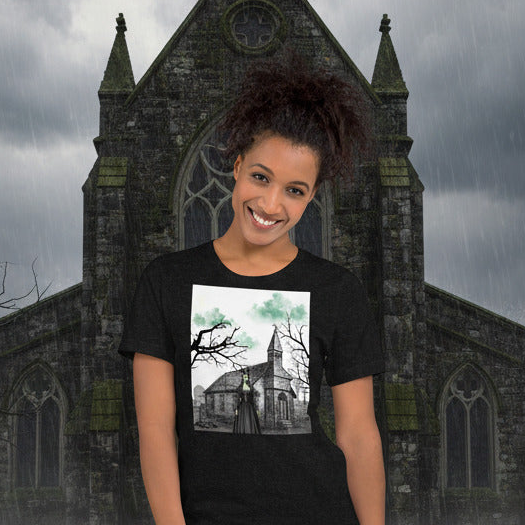 Person wearing a black t-shirt with a church design in front of a gothic-style building.