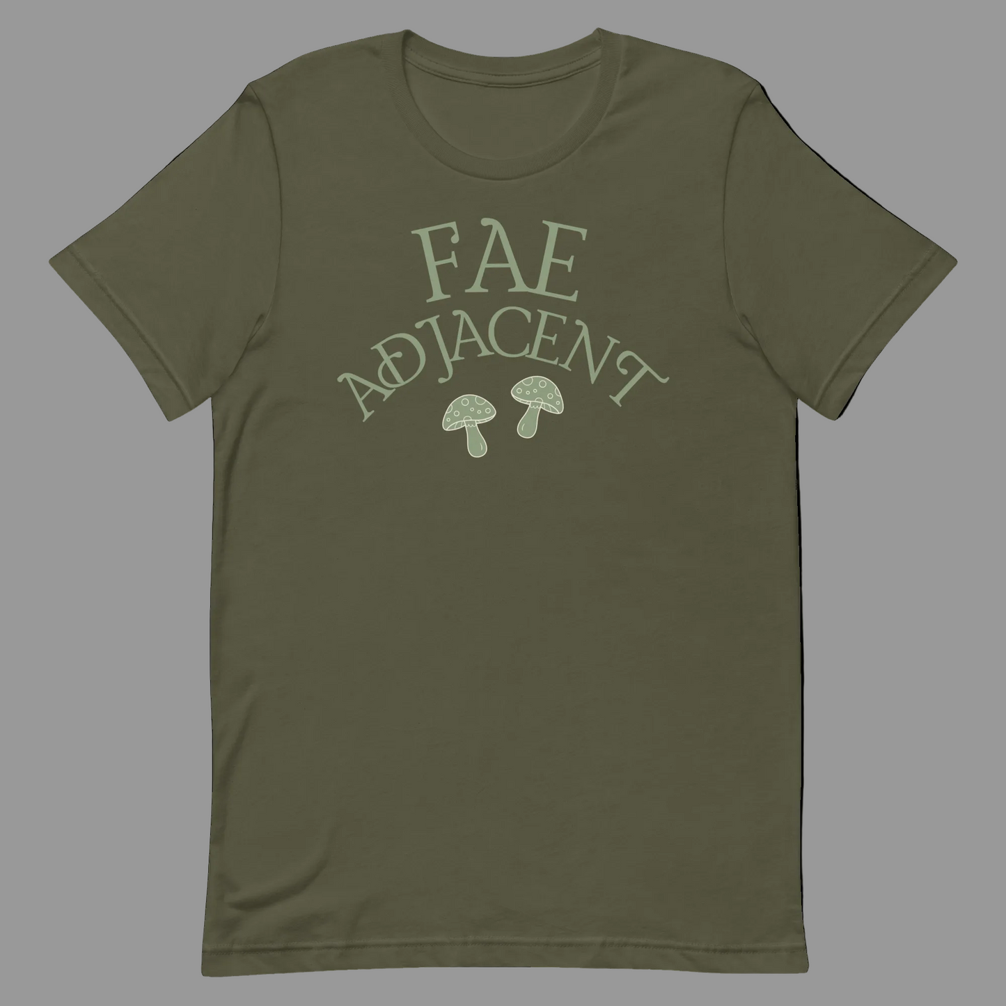 An olive green short-sleeve t-shirt with a light sage green graphic on the chest that reads 'FAE ADJACENT' above two small mushrooms, shown on a plain white background.