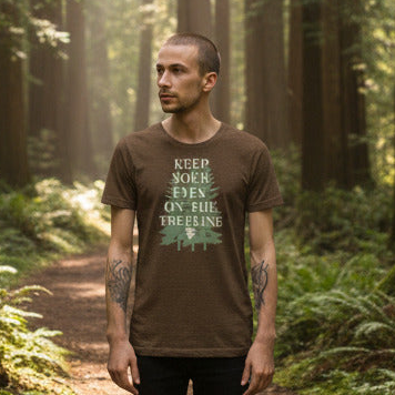 Man wearing a brown t-shirt with a graphic design in a forest