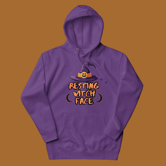 A purple pullover hoodie with a graphic on the chest showing a witch hat above the text 'RESTING WITCH FACE' in orange and black, displayed on a clean white background.
