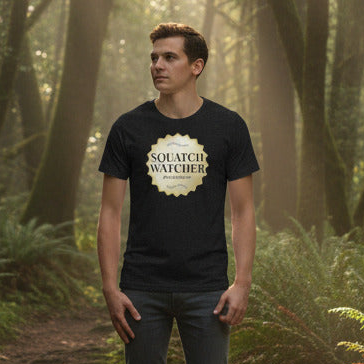 Man wearing a black t-shirt with 'Squatch Watcher' design in a forest setting