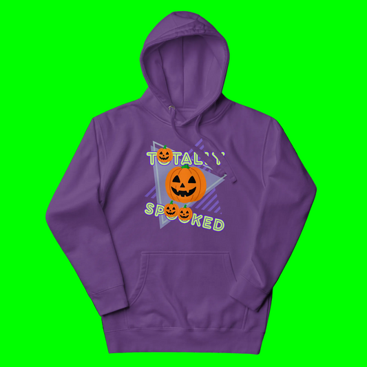 A purple pullover hoodie with a Halloween graphic on the chest featuring jack-o'-lanterns, stars, and the text 'TOTALLY SPOOKED' in green and yellow.